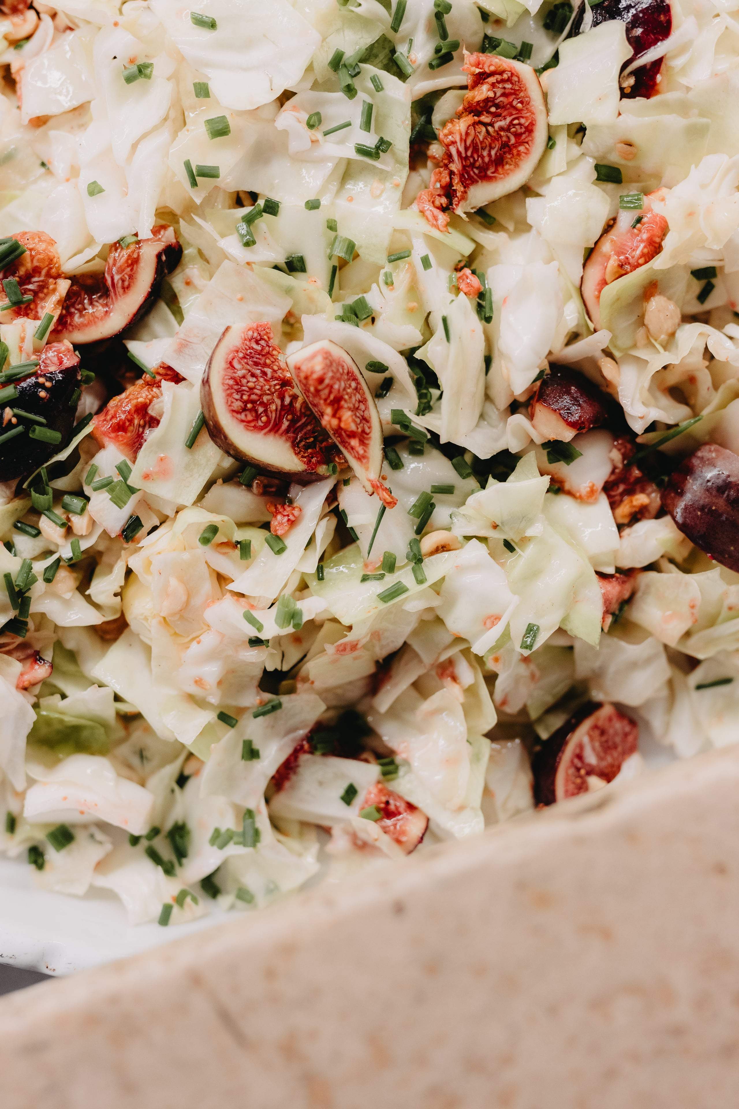Krautsalat mit frischen Feigen und Schnittlauch in einer Schale, nah