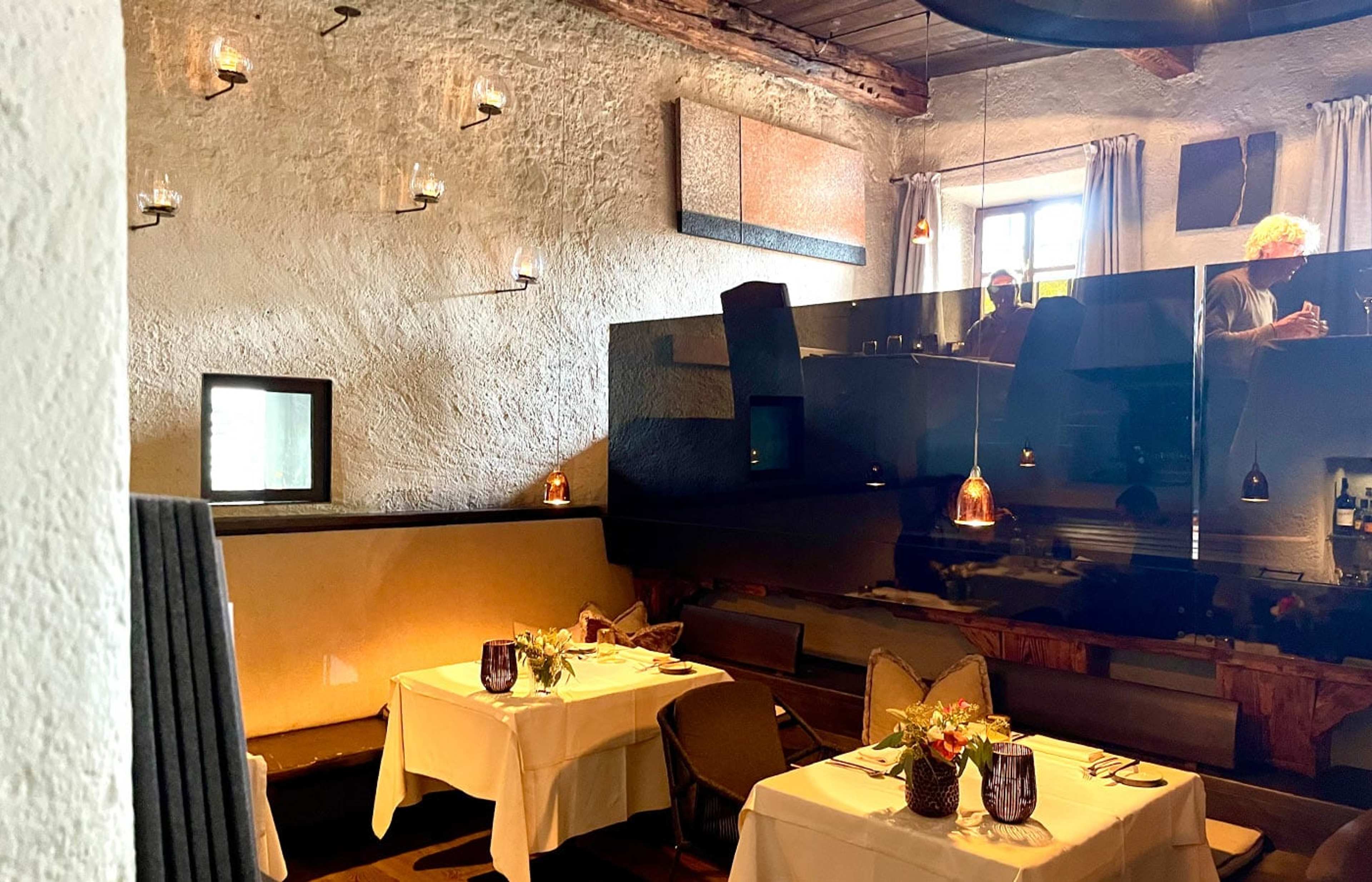 Restaurant mit weiß gedeckten Tischen vor einer hellen Steinwand
