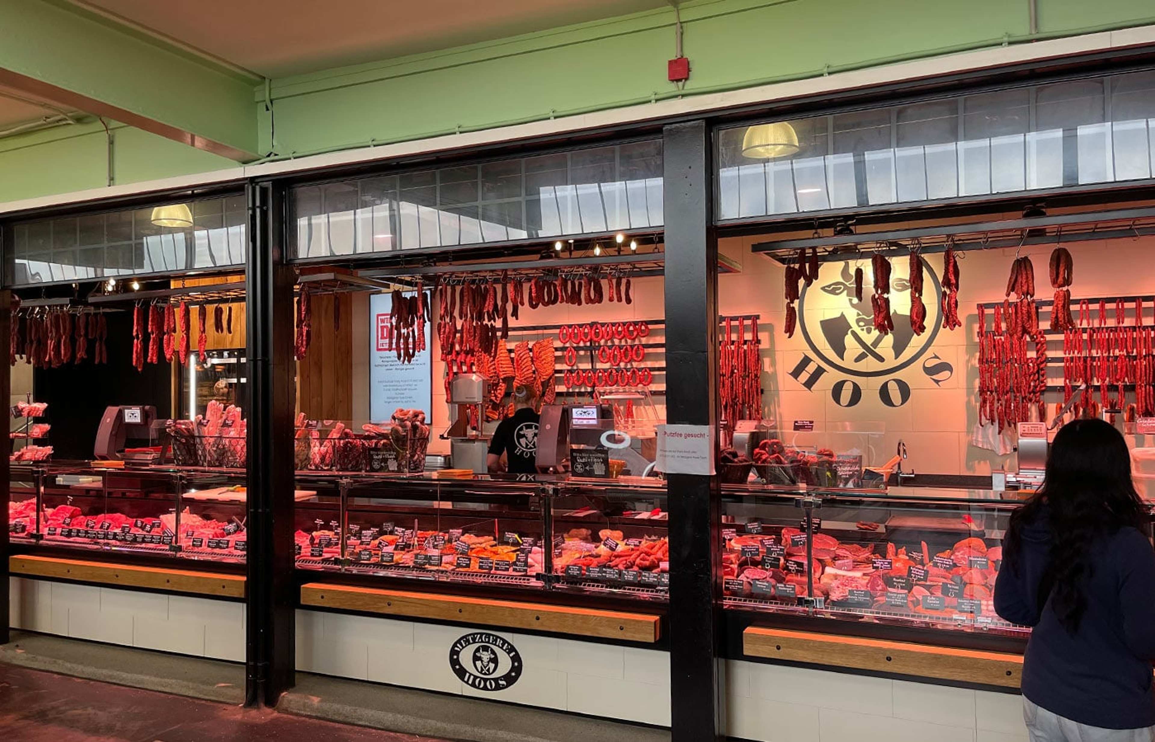 Metzgertheke mit hängenden Würsten in einer Markthalle