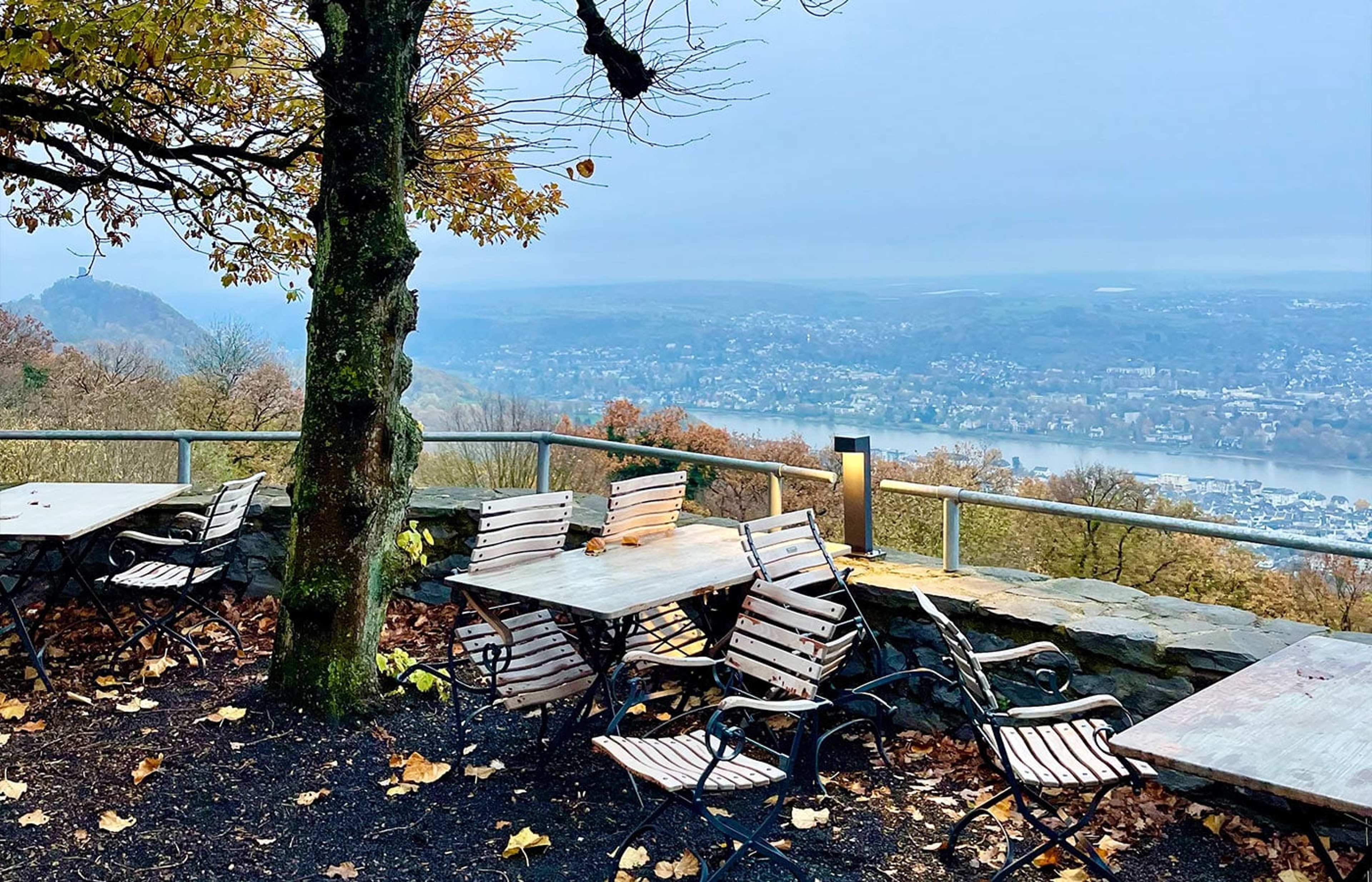 Leere Terrassenstühle über einem weiten Blick auf das Rheintal im Herbst