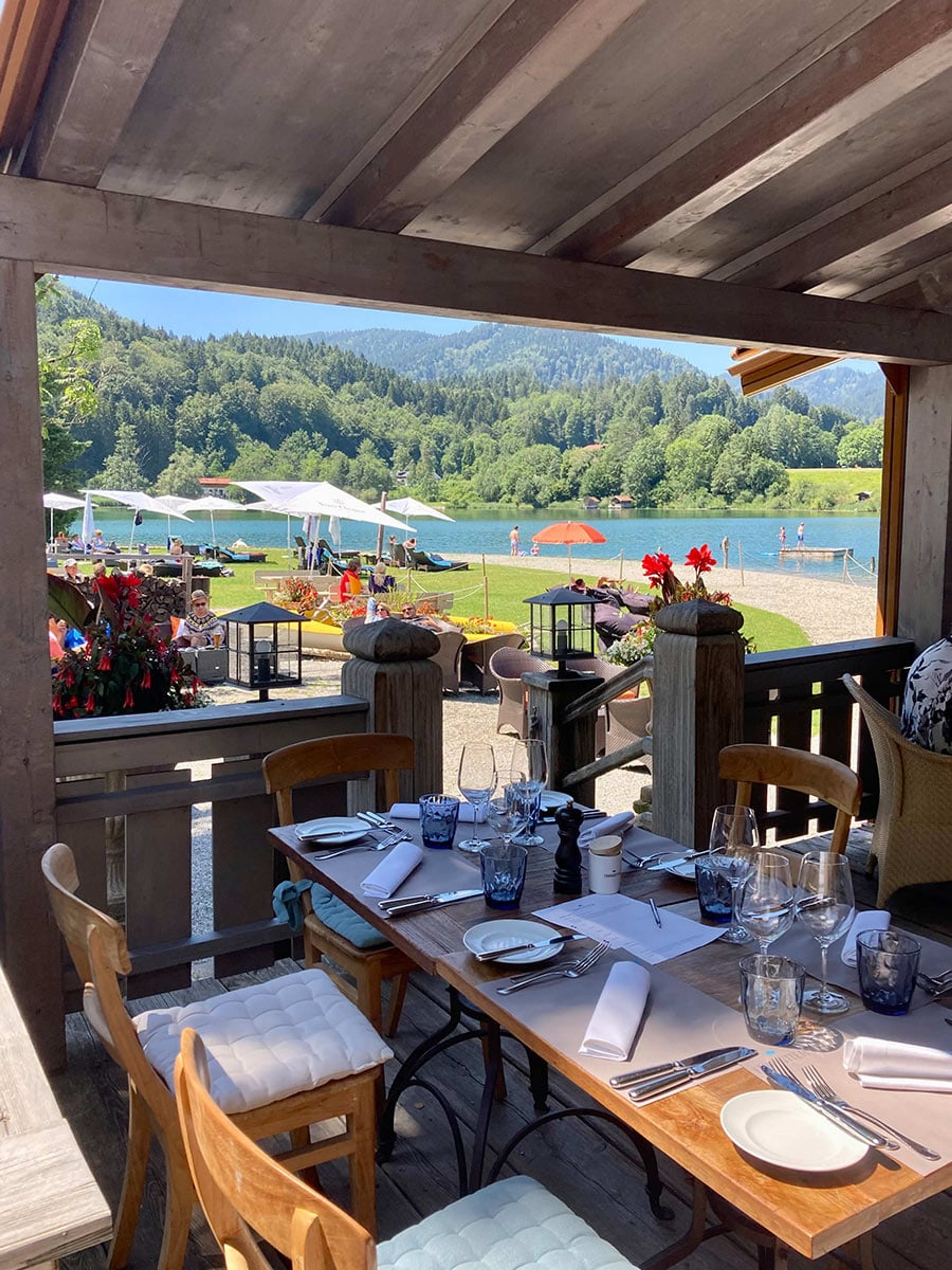 Gedeckter Tisch auf einer Holzveranda mit Blick auf einen See