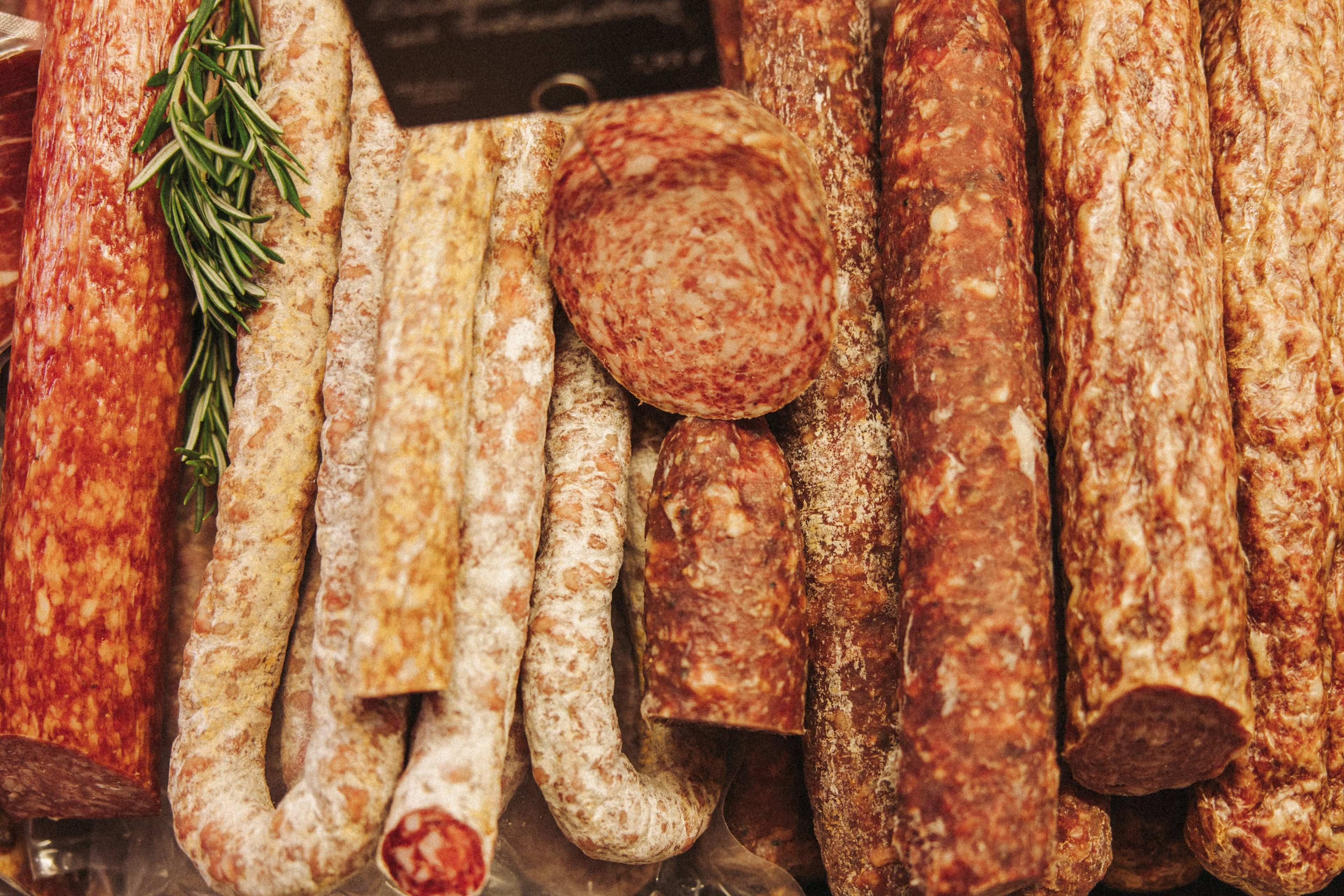 Auswahl an Salami mit einem Rosmarinzweig in der Auslage