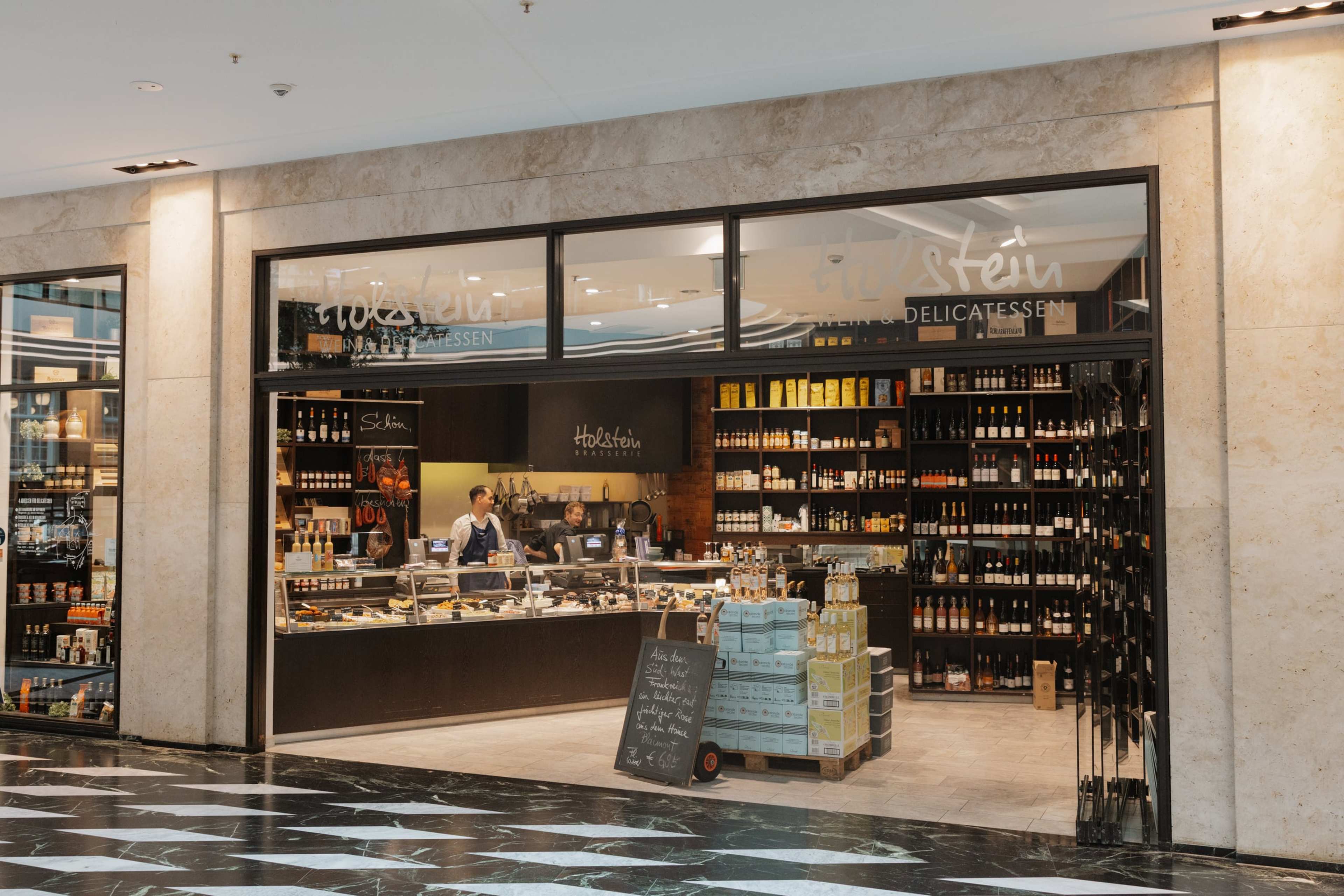 Ladenfront von Holstein Wein und Delicatessen in den Münster Arkaden mit Theke und Weinregalen