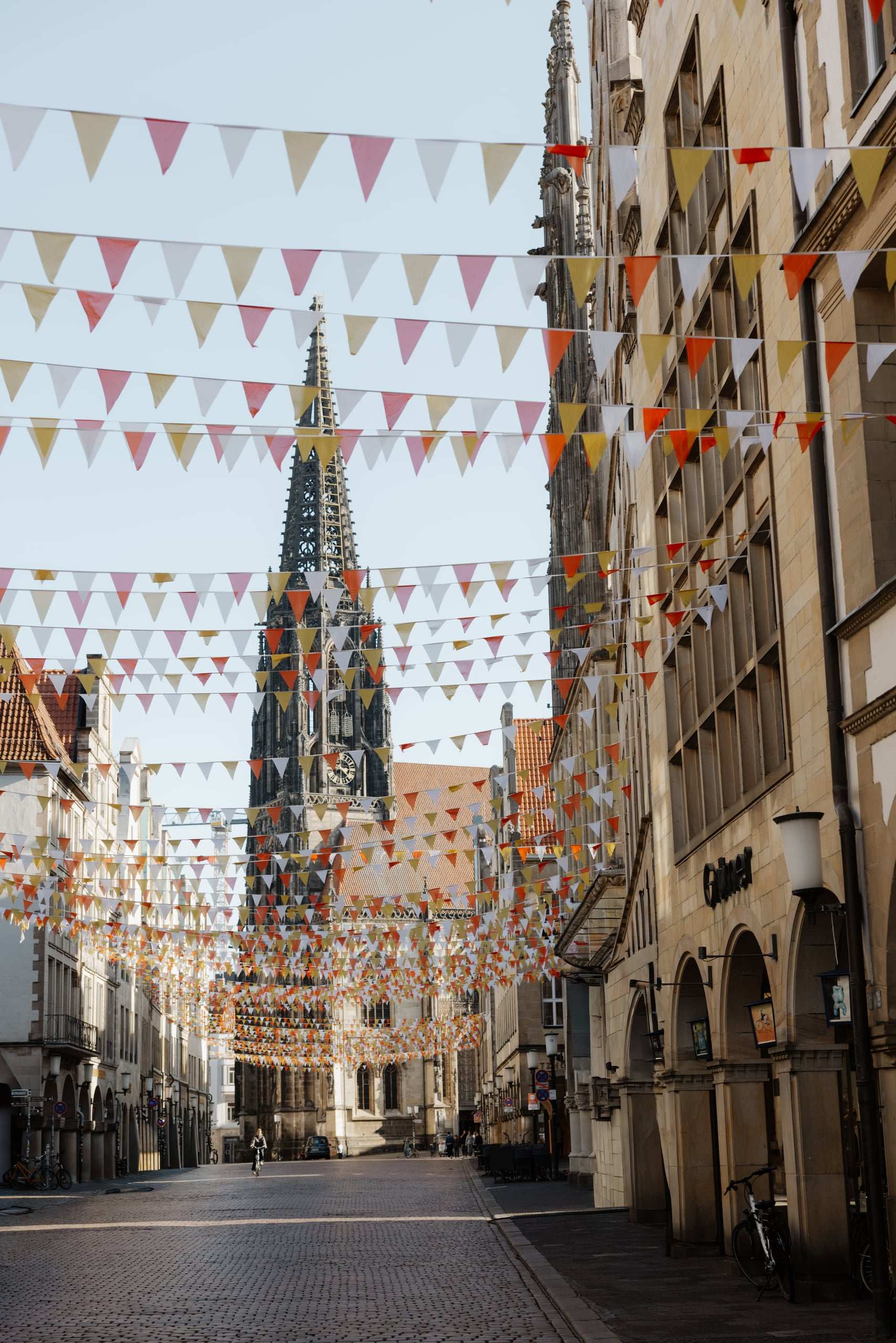 Blick über den Prinzipalmarkt in Münster mit bunten Wimpelketten auf den Turm der Lambertikirche