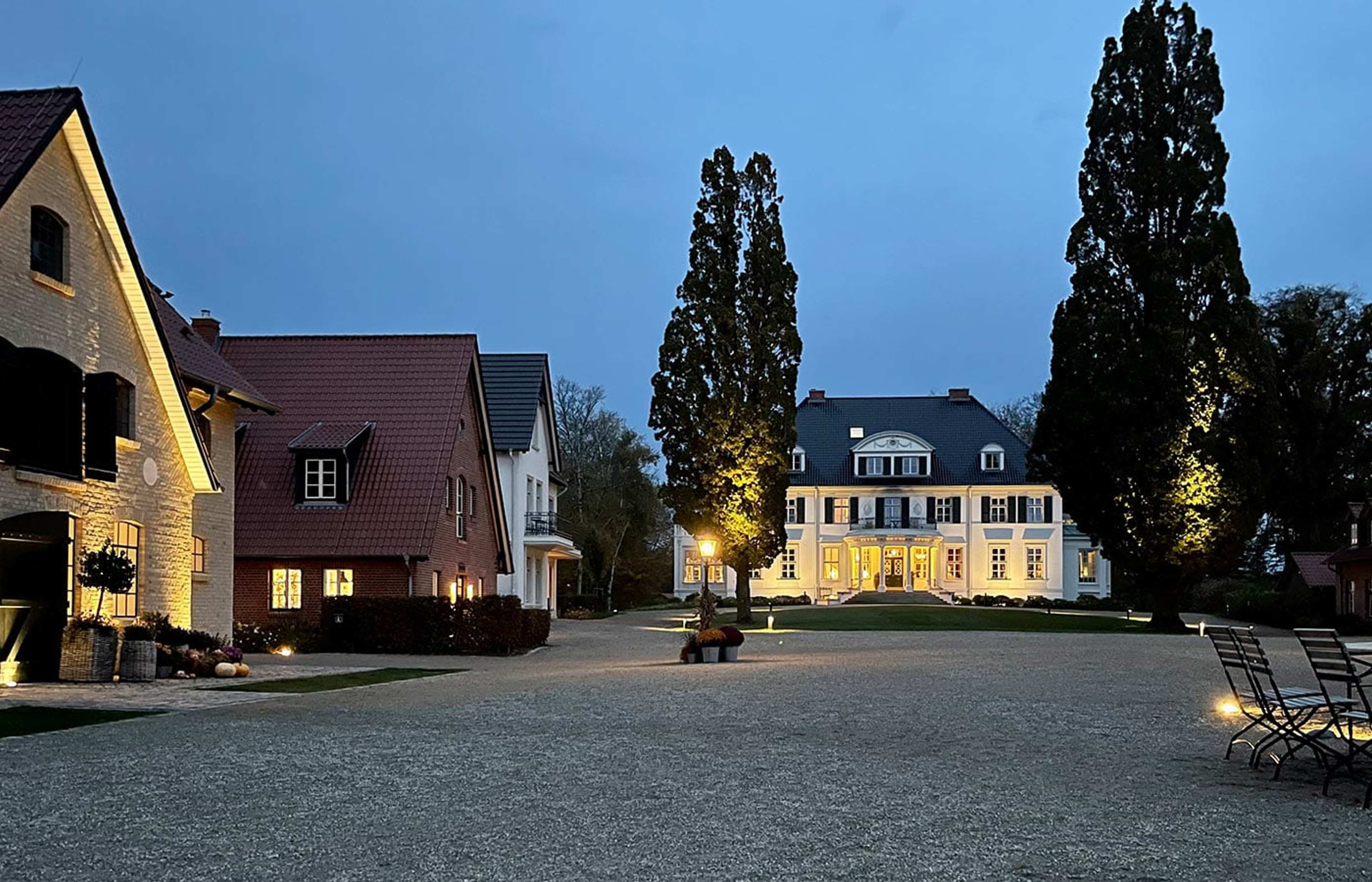 Gutshof mit beleuchtetem Herrenhaus in der Dämmerung