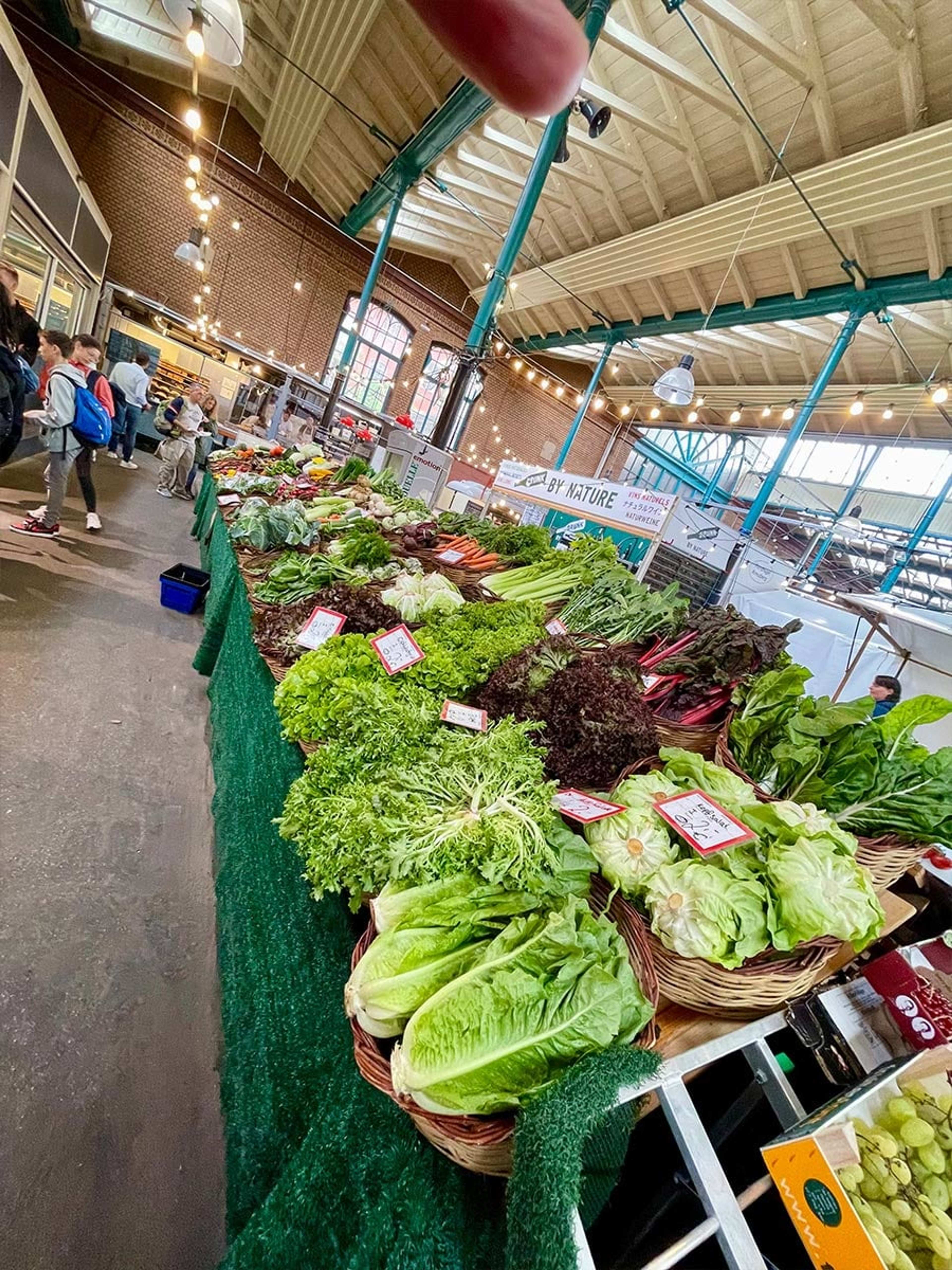 Marktstand mit Salatköpfen und Kräutern in einer Markthalle
